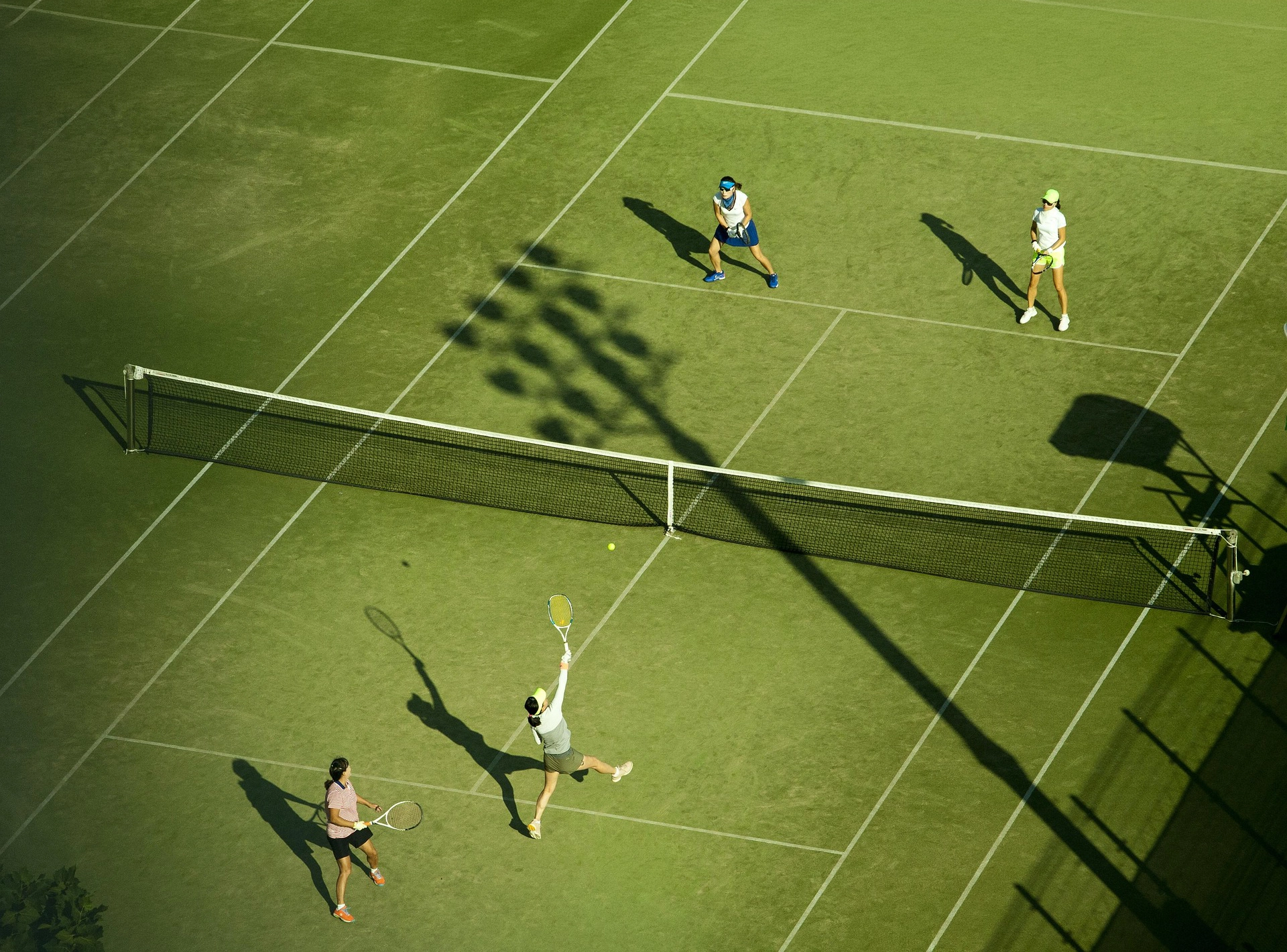 Tennisspieler beim Aufschlag im Doppel auf einem Hartplatz aus der Vogelperspektive